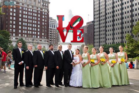 Wedding Party Love Park for photos before church on white trolley rental black tuxedo green dress yellow flowers 12 people for 23 passenger Victorian trolley in Philadelphia